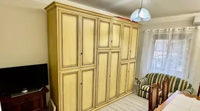 a large wooden cabinet in a living room with a chair at Elegant Home in Rome Appio, Wi-Fi, Subway in Rome