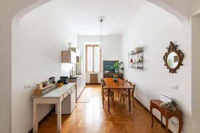 a kitchen and dining room with white walls and wooden floors at Le Stanze di Margot con Parcheggio Privato in Rome