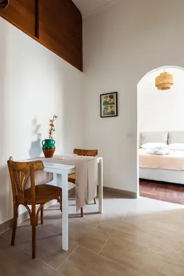 a white dining room with a table and a bed at Le Stanze di Margot con Parcheggio Privato in Rome