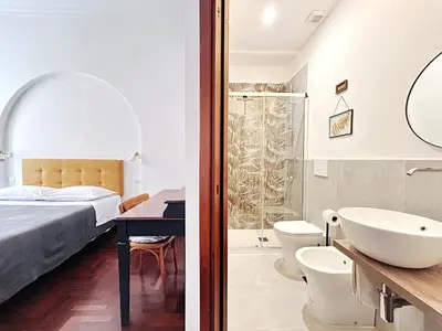 a bedroom with a bed and a bathroom with a sink at Le Stanze di Margot con Parcheggio Privato in Rome