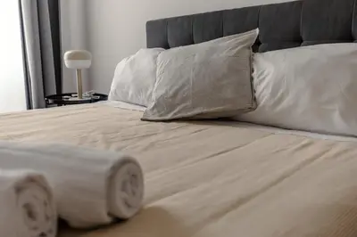 a bed with white pillows and a gray headboard at Domus Merulana 209 Colosseum Apt in Rome