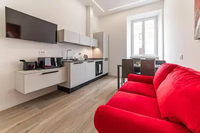a living room with a red couch and a kitchen at Vatican Suites Apartment - Vatican City in Rome