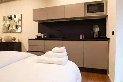 a bedroom with a white bed and a kitchen at Maison Ametie in Rome