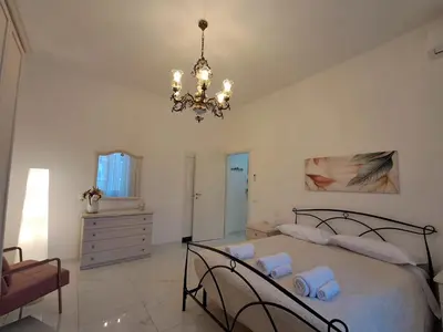 a bedroom with a large bed and a chandelier at De Camillis Apartments in St Peter in Rome