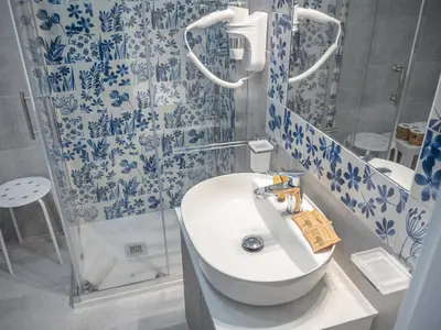 a bathroom with a white sink and blue and white tiles at De Camillis Apartments in St Peter in Rome