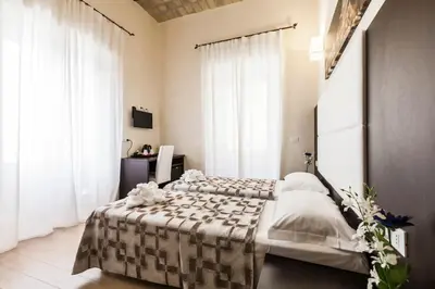 a bedroom with two beds and white curtains at Stardust Rome Guest House in Rome