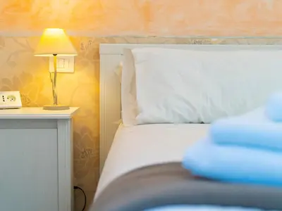 a bed with a white pillow and a lamp on a table at Salotto Piramide in Rome