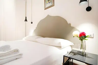 a bedroom with a white bed with a vase of flowers on a table at Elegantis Eat Pray and Love in Rome - Near Navona Square and Campo de' Fiori in Rome