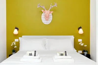 a bedroom with a white bed with a green wall at Monti Apartments - My Extra Home in Rome