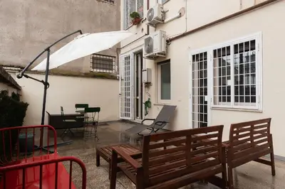 a patio with two benches and an umbrella at GuestHost - Cozy Ostiense Flat with Terrace! in Rome
