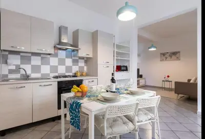 a kitchen with a white table and chairs and a kitchen with white cabinets at Trastevere 2Rooms with Balcony in Rome