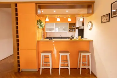 an orange kitchen with two stools at a bar at Fontana di Trevi Modern Apartment in Rome