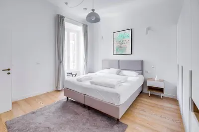 a white bedroom with a large bed and a rug at Charming Vatican Apartment with Balcony 6B in Rome