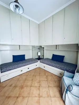 two beds in a room with white cabinets and blue pillows at Casa San Pietro Rome Vatican in Rome