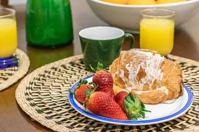 a plate of strawberries and croissants and a cup of orange juice at San Giovanni Metro A Cozy Suite WIFI AC in Rome