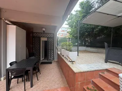 a patio with a table and chairs and an umbrella at Grazia s Elegant Roman Haven with Terrace in Rome