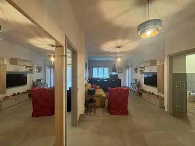 a living room with red chairs and a television at Grazia s Elegant Roman Haven with Terrace in Rome