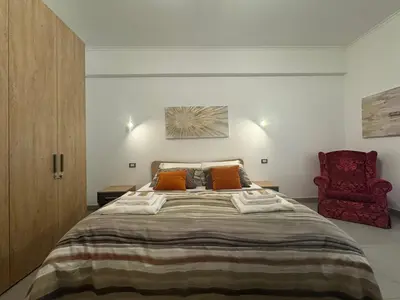 a bedroom with a large bed and a red chair at Grazia s Elegant Roman Haven with Terrace in Rome