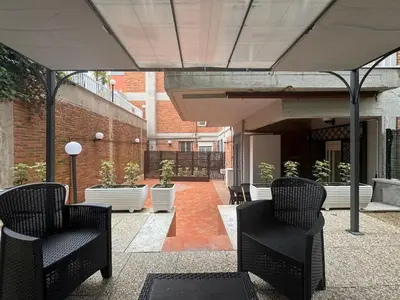 an outdoor patio with black chairs and a building at Grazia s Elegant Roman Haven with Terrace in Rome