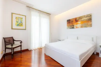 a white bedroom with a bed and a chair at Romano Apartments - 