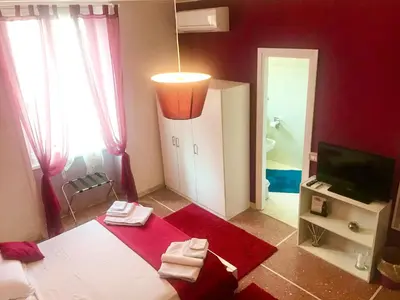 a red room with a bed and a television and a bathroom at A Casa Di Giallo B&B in Rome