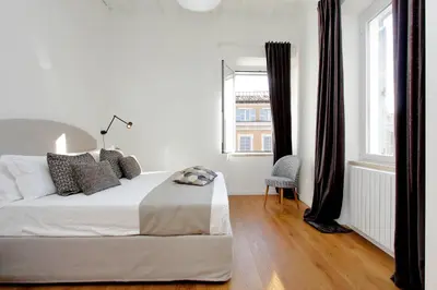 a white bedroom with a bed and a window at Torre Argentina in Rome