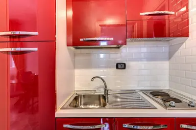 a kitchen with red cabinets and a sink at Apartment near Via Veneto in Rome