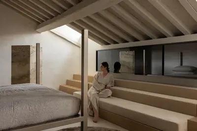 a woman sitting on stairs next to a bed at Nomos Hotel in Rome