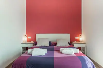 two beds in a room with a red wall at B&B Il Giardino di Gabri in Rome