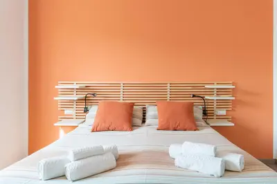 a bed with two pillows and an orange wall at B&B Il Giardino di Gabri in Rome