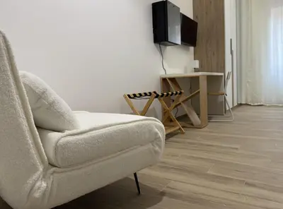 a living room with a chair and a flat screen tv at Nella House Roma in Rome