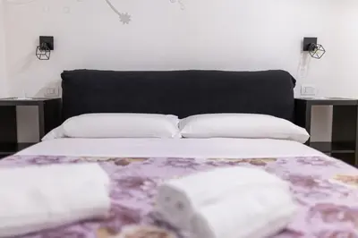a bed with a black headboard and white pillows at Termini Roma Imperiale in Rome