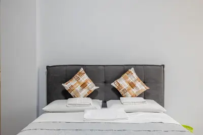a bed with a gray headboard with four pillows at Star Guest House Rome in Rome
