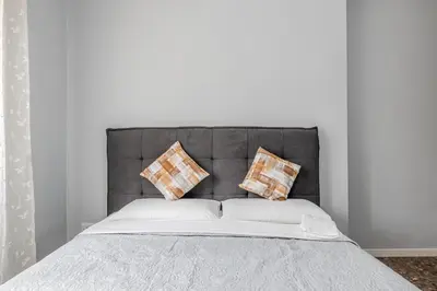 a bed with a gray headboard with pillows on it at Star Guest House Rome in Rome