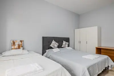 a bedroom with two beds with white sheets and a dresser at Star Guest House Rome in Rome