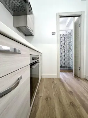 a kitchen with wooden floors and white walls at Spagna Home in Rome