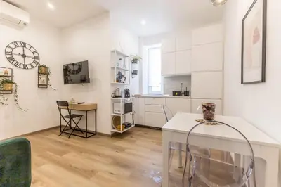 a kitchen with white cabinets and a clock on the wall at Urbano 29 apartment in Rome