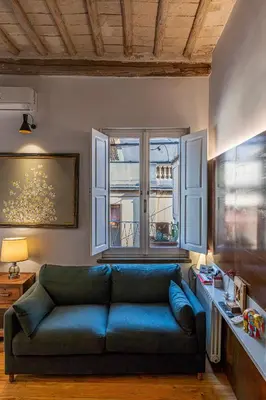 a living room with a blue couch and a window at Giulia's House, Monti in Rome