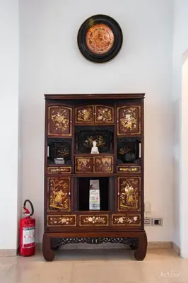 a wooden cabinet with a clock on the wall at Magikrooms Domus in Rome
