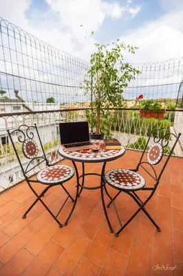 a table and two chairs with a laptop on a balcony at Magikrooms Domus in Rome