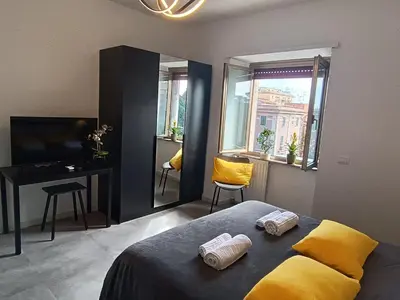 a bedroom with a bed and a desk and windows at Casa Vacanze Bianca - Metro A - Furio Camillo in Rome