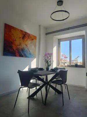 a dining room with a table and chairs and a painting at Casa Vacanze Bianca - Metro A - Furio Camillo in Rome