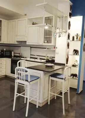 a kitchen with white cabinets and a counter and chairs at large Vatican loft near the metro in Rome