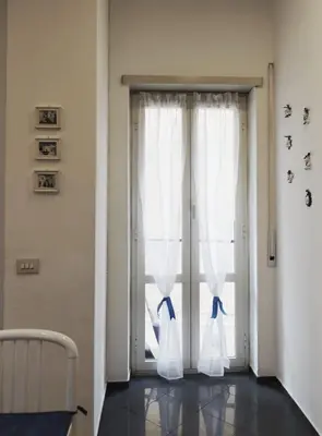 a window with white curtains with blue bows at large Vatican loft near the metro in Rome