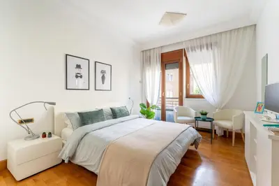 a white bedroom with a large bed and a desk at The Roman Sketchpad, Few Steps from Villa Borghese in Rome