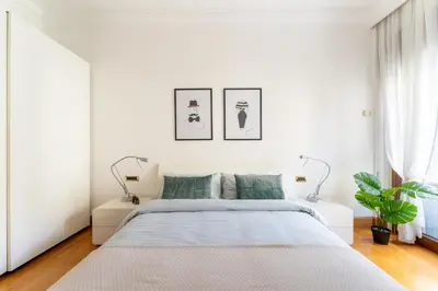 a white bedroom with a bed and two lamps at The Roman Sketchpad, Few Steps from Villa Borghese in Rome