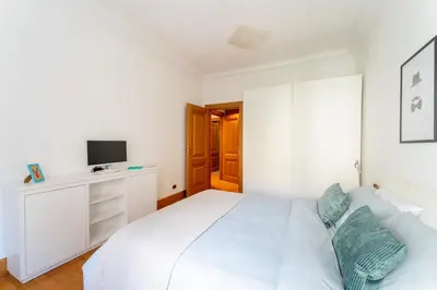 a white bedroom with a white bed and a tv at The Roman Sketchpad, Few Steps from Villa Borghese in Rome