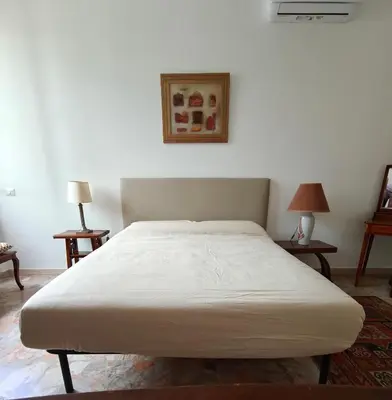 a white bed in a room with two tables at CasAdelia in Rome