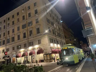 a green train traveling past a building at night at Sweet Home Inn in Rome