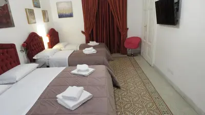a hotel room with three beds and a television at Sweet Home Inn in Rome